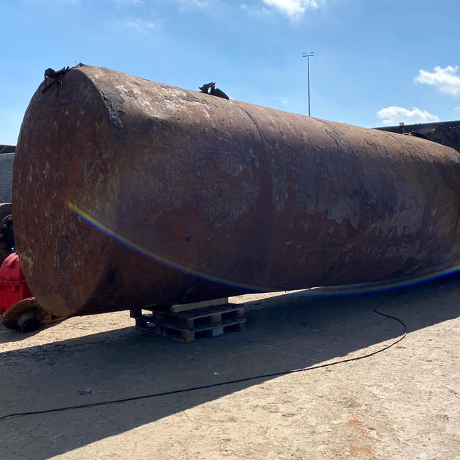 stor-jerntoende-jernskrot-metalskrot-tjen-penge-skrotspecialisten Stor jerntønde der skal skrottes. Der er blå himmel og jerntønden er løftes op på nogle paller.
