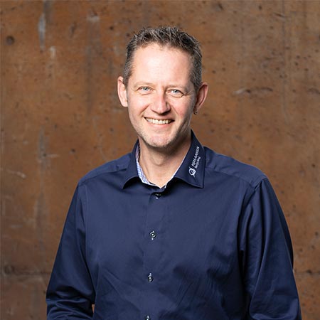 Portrætbillede af Martin Kirk der er Markedskonsulent for Vest, Midt- og Østjylland hos HJHansen. Han er iført mørkeblå skjorte med HJHansen Recycling Group logo på.