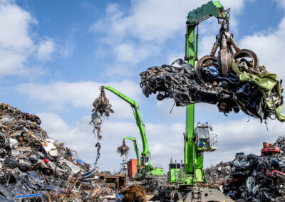 Tre kraner løfter skrot, omringet af skrot v/ HJHansen Recycling