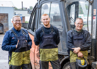 Tre mænd iført arbejdstøj i gult og blåt.