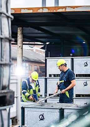 To mænd i arbejdstøj med gule hjelme der samarbejder