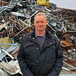 Skrotspecialisten-Preben HJHansen, Skrotspecialisten. Billede af mand foran jern- og metal skrotbunke.